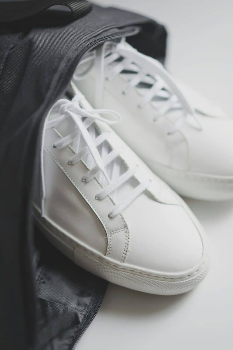 White sneakers resting on a grey knit fabric