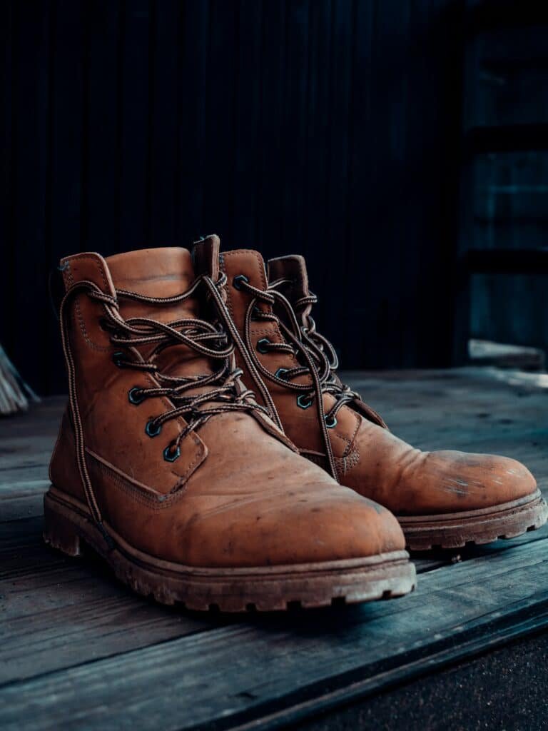 Pair of worn brown leather lace-up boots on a wooden floor