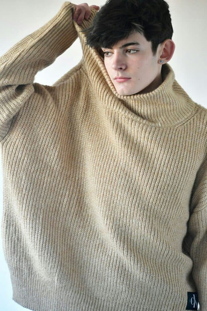Young man in an oversized cream knit sweater