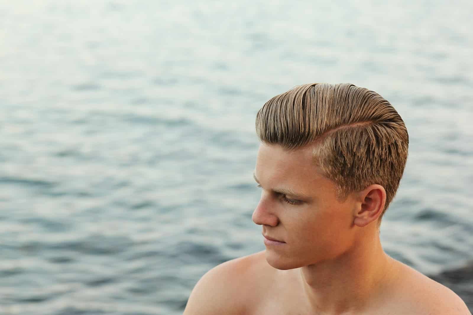 Young man with side-parted hair by the water